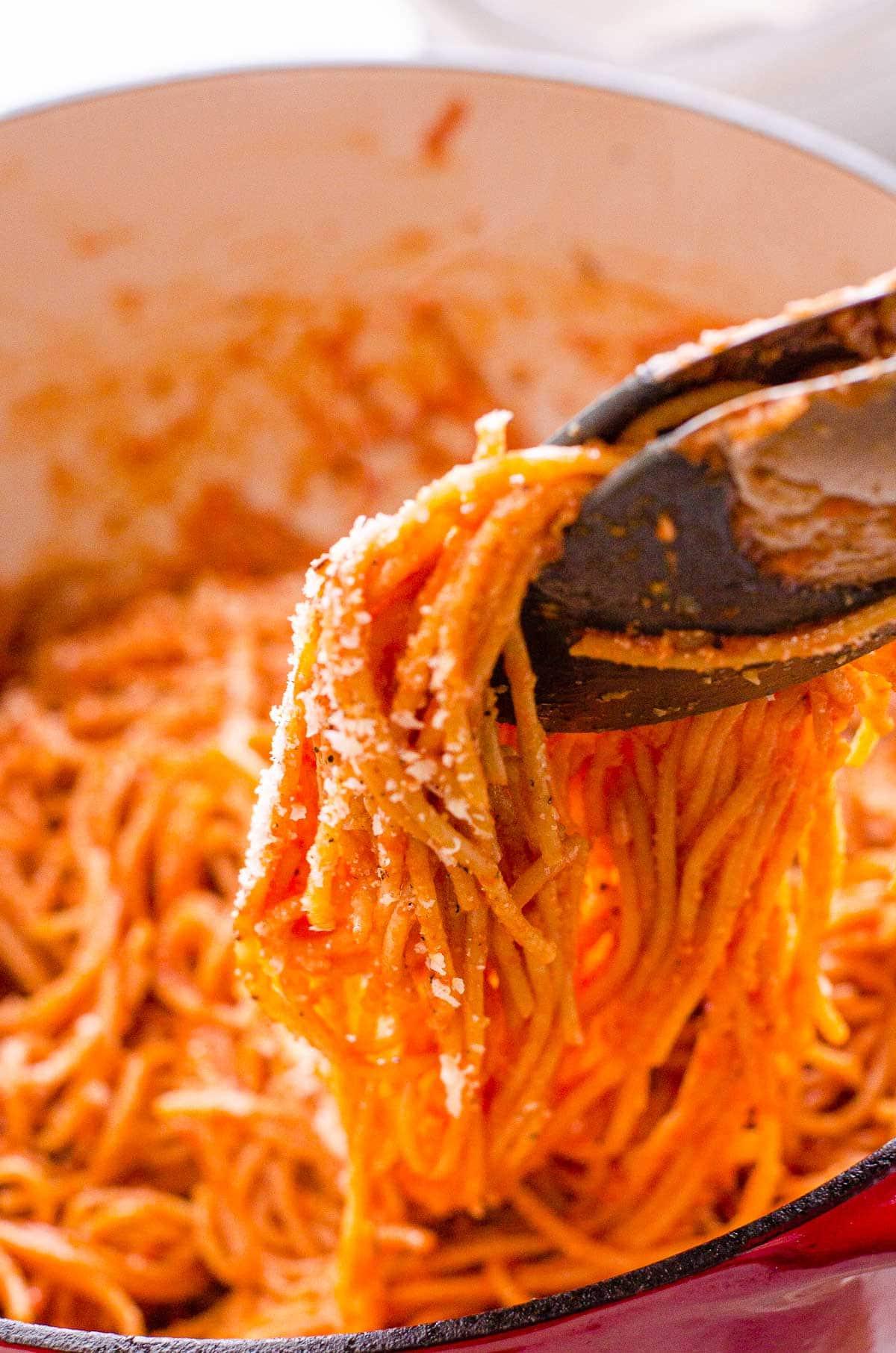 Easy spaghetti recipe being dished out of a pot with tongs.
