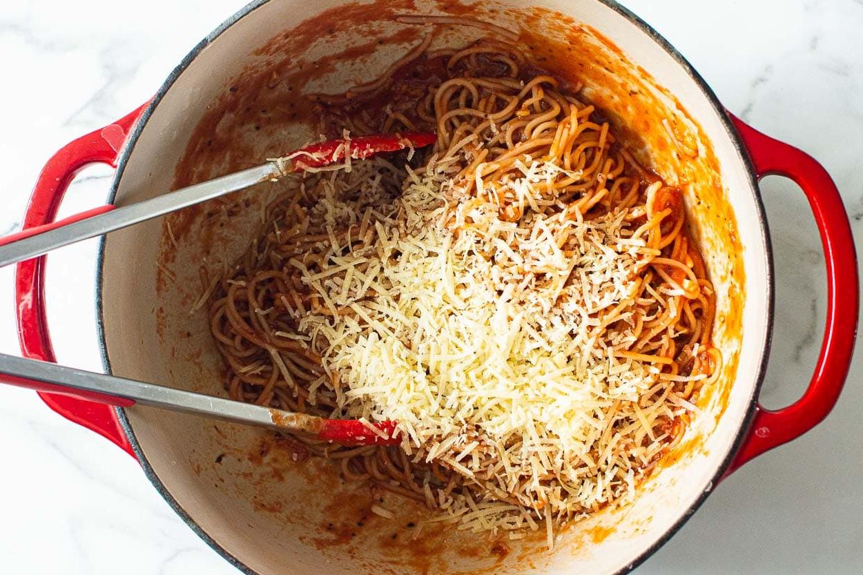 Parmesan cheese with spaghetti noodles in a large pot.